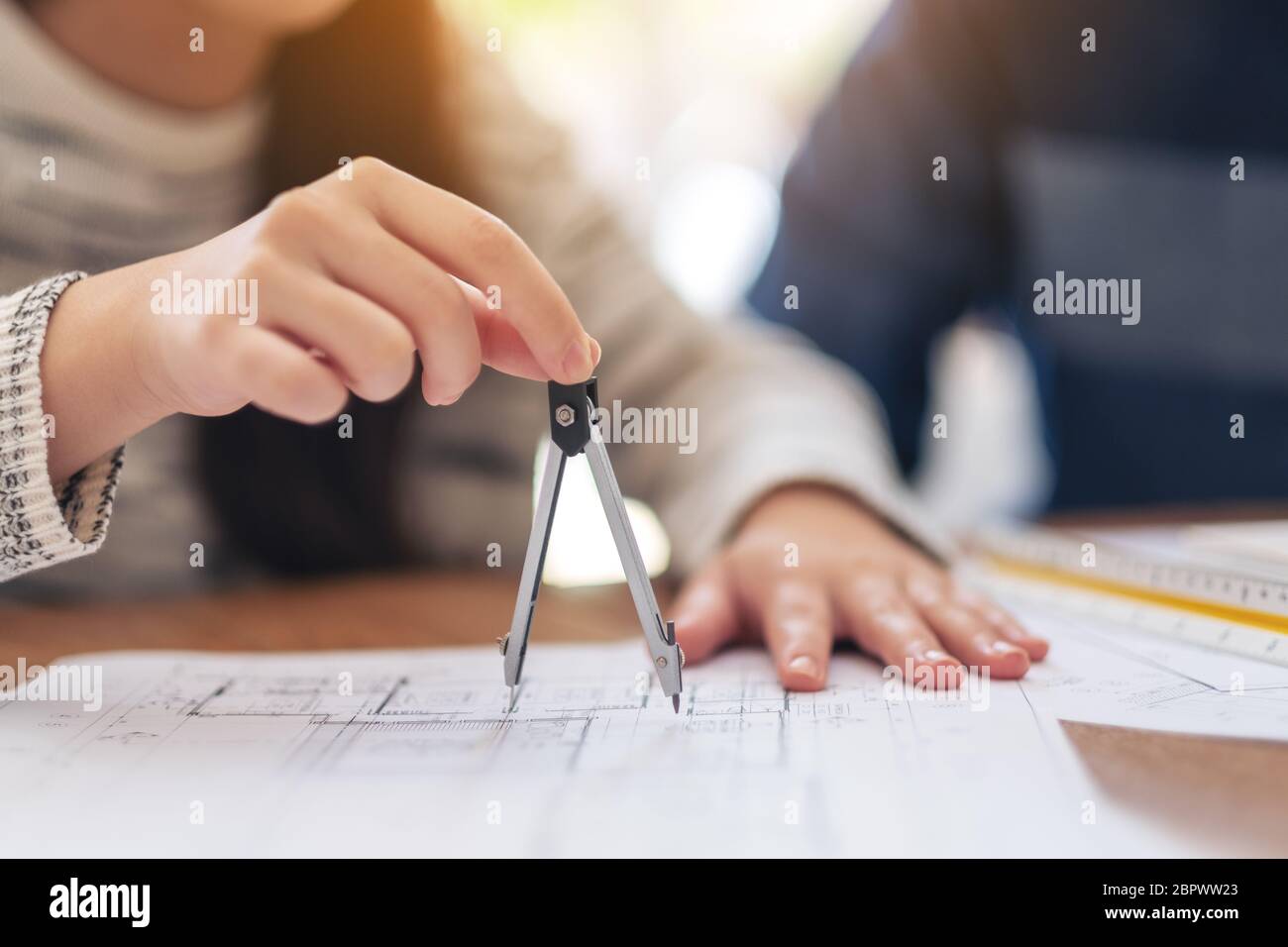 An architect using compass to draw and measure shop drawing in office Stock Photo