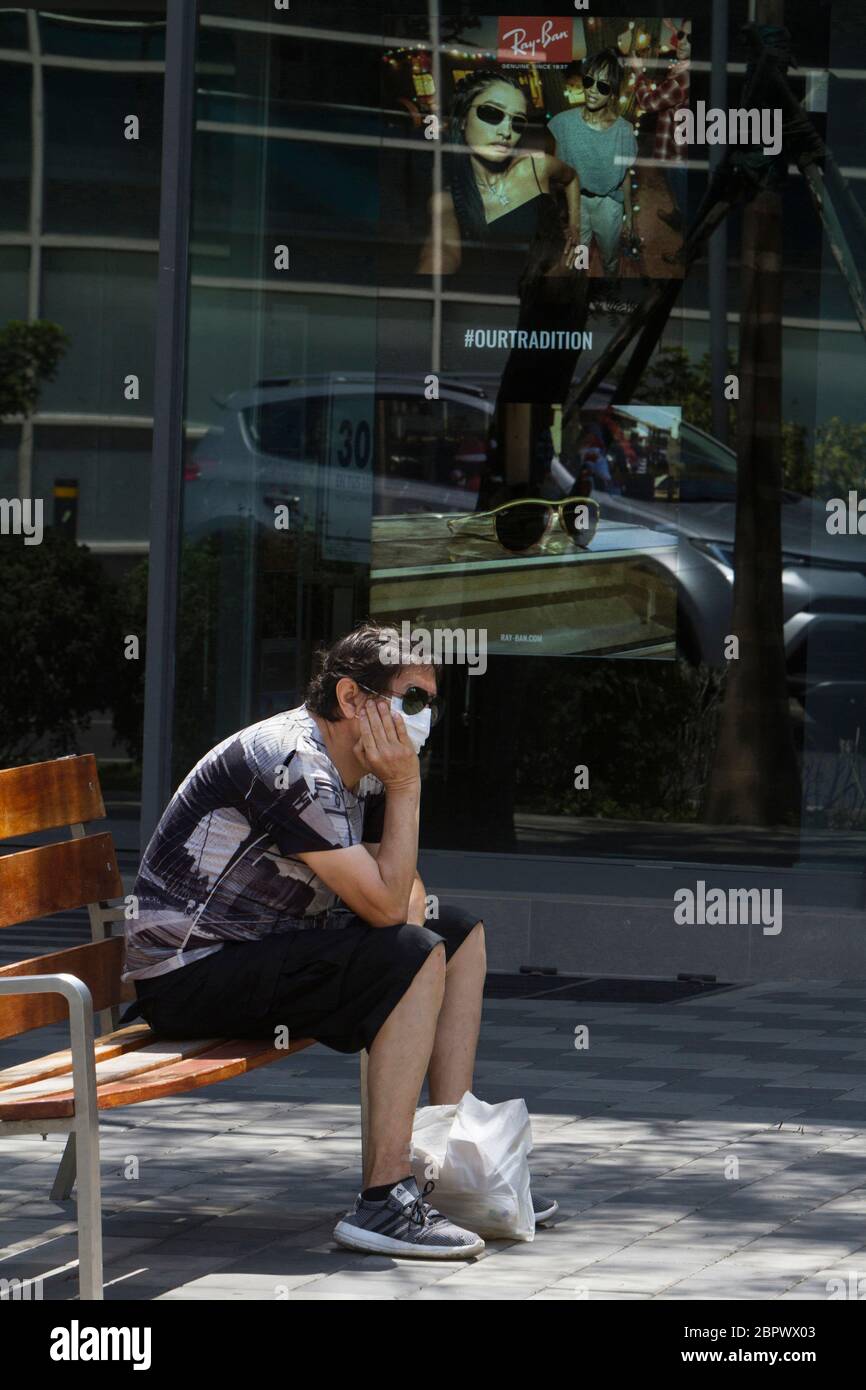 A man rests on a bench opposite to an advertisment during the national state of emergency as a response to the COVID-19 pandemic in Lima, Perú. According to the Peruvian Government 21,648 people have been infected and 364 have died as of April 24, 2020. Yesterday Perú enacted 15 more days of mandatory quarantine to a total of 59 days in an attempt to prevent the spread of the virus. Stock Photo