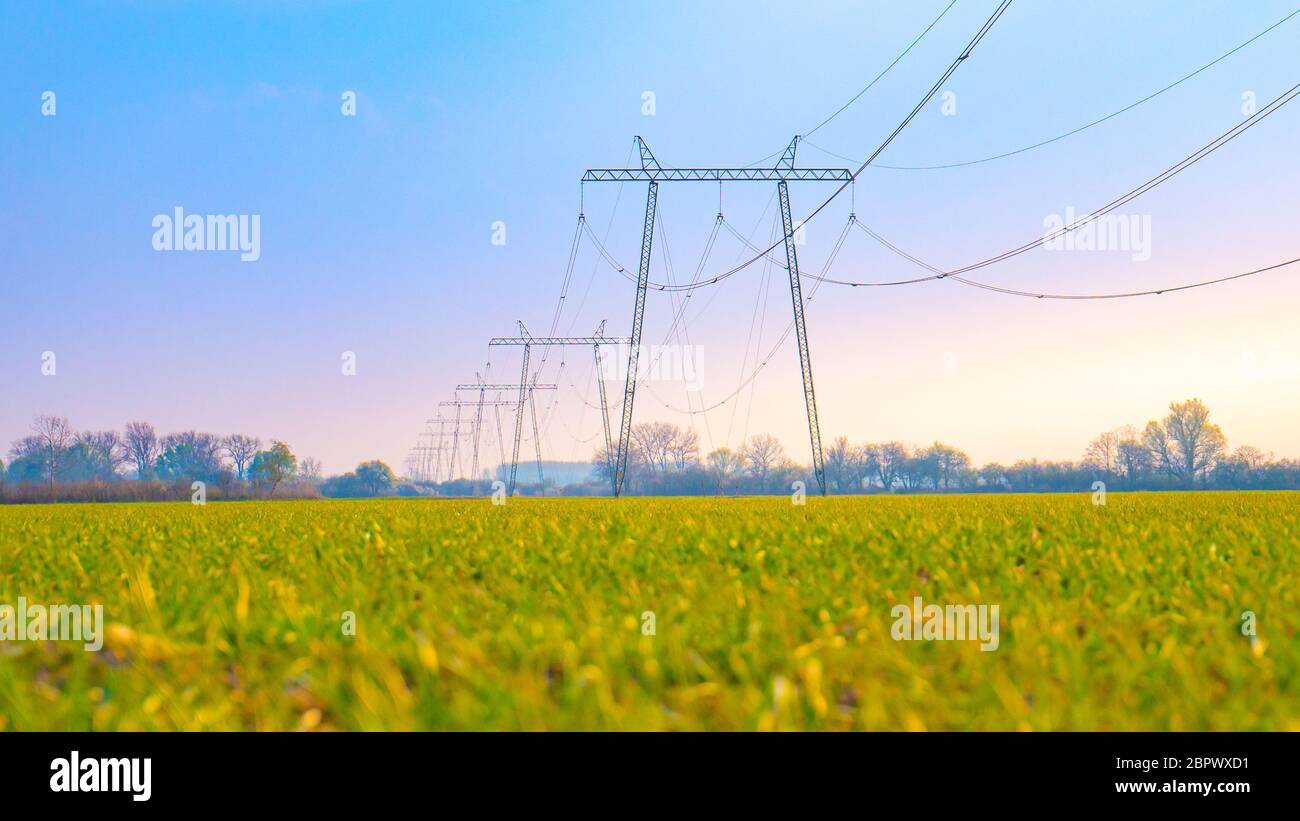 High voltage lines and power pylons in a green agricultural landscape ...