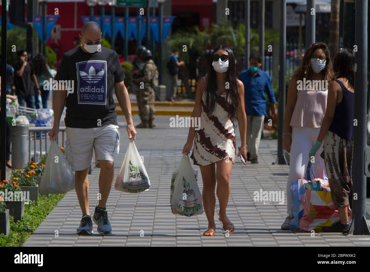 A group of people wearing masks carry groceries from the supermarket during the national mandatory quarantine as a response to the COVID-19 pandemic in Lima, Peru. Since the installment of the measure back in March the government have struggled to stop the spread of the virus especially in public areas such as markets. 33,931 people have been infected and 943 have died as of April 29, 2020. Stock Photo