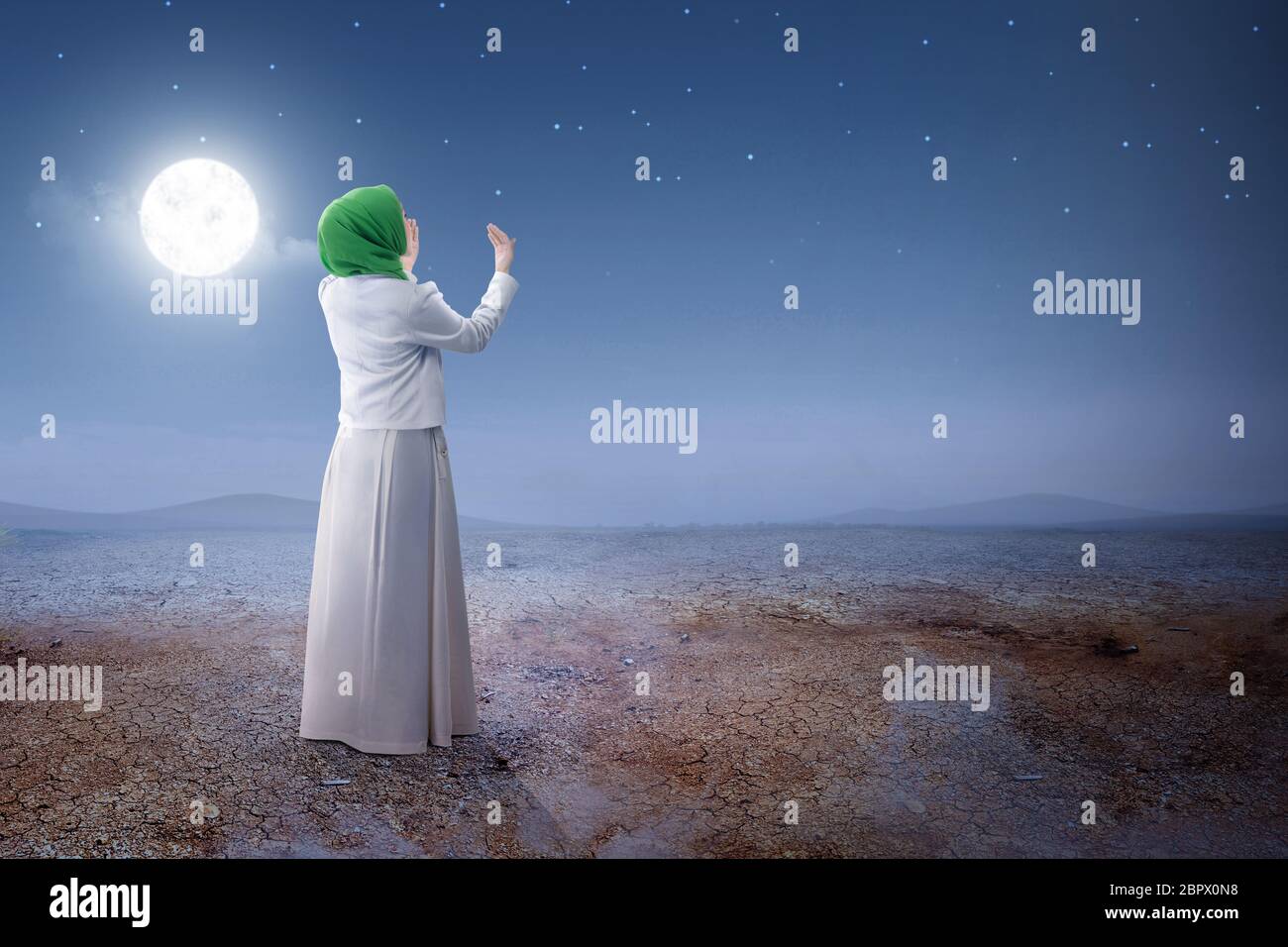 Rear view of asian muslim woman in veil raised hands and praying on the ...