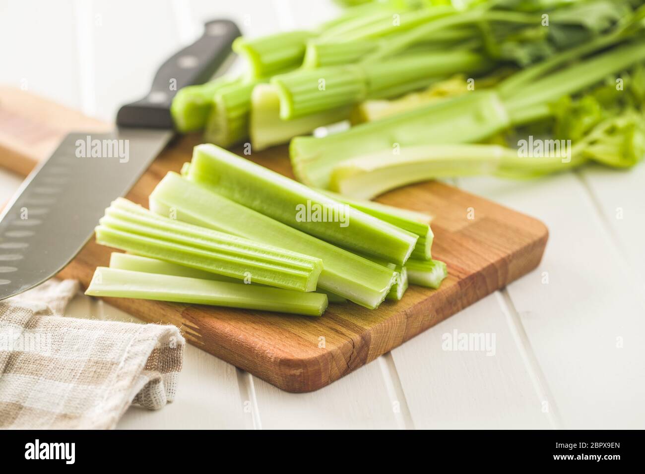 Celery sticks. Cutting celery stalks on cutting board. Stock Photo