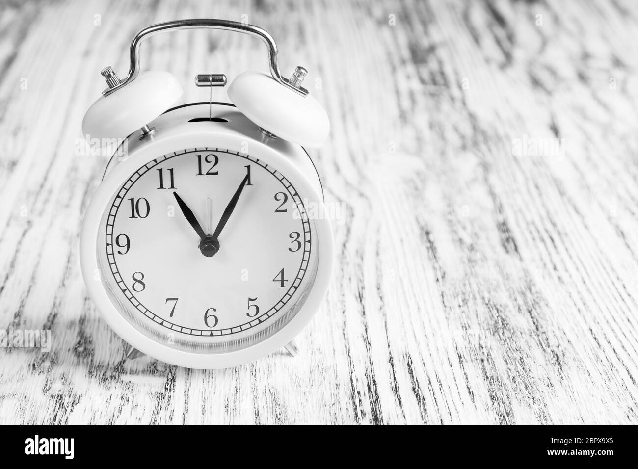 Classic analog alarm clock on a wooden texture background. Dramatic black and white view. Copyspace. The concept of the financial coronavirus crisis Stock Photo