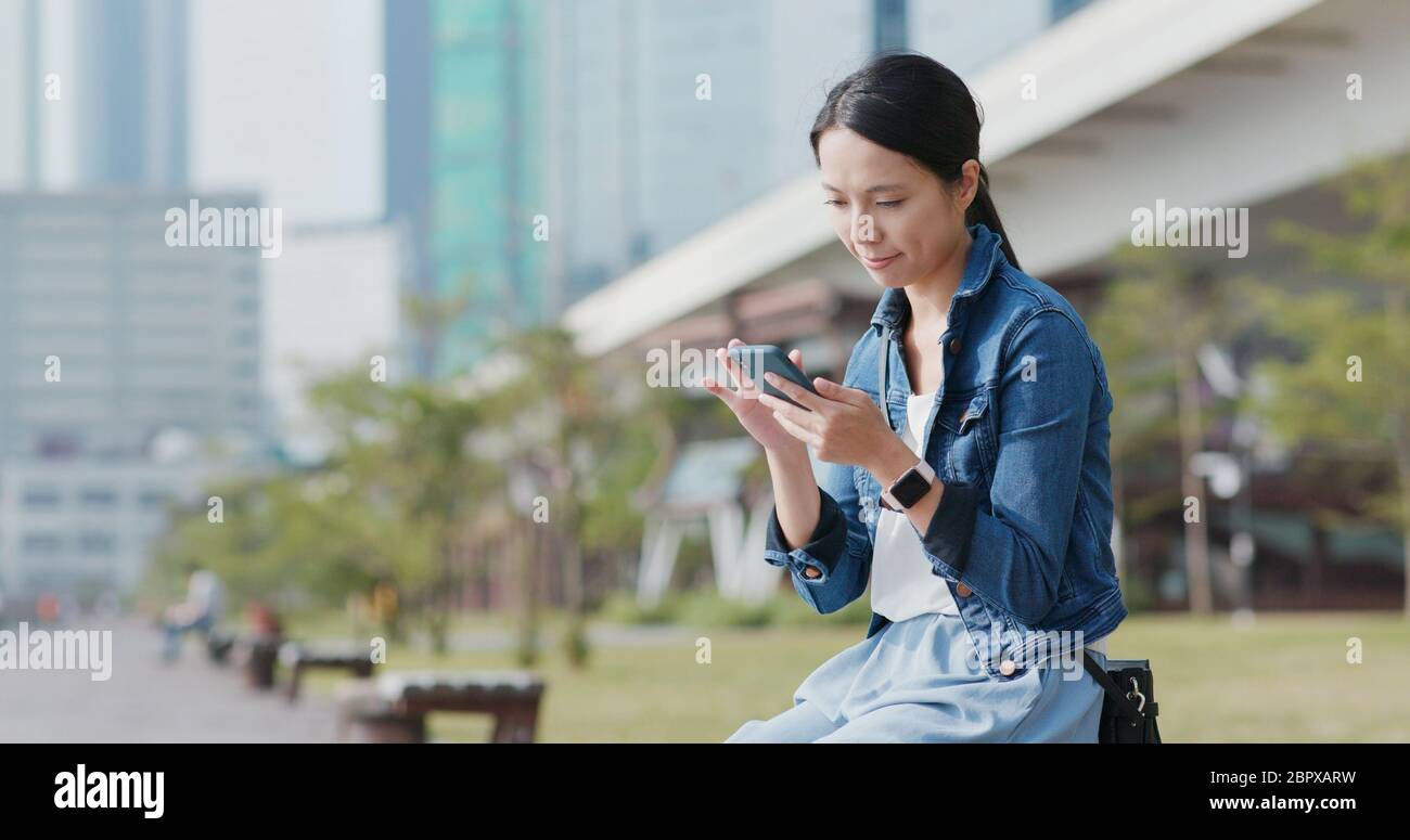 Woman look at mobile phone in the city park Stock Photo - Alamy