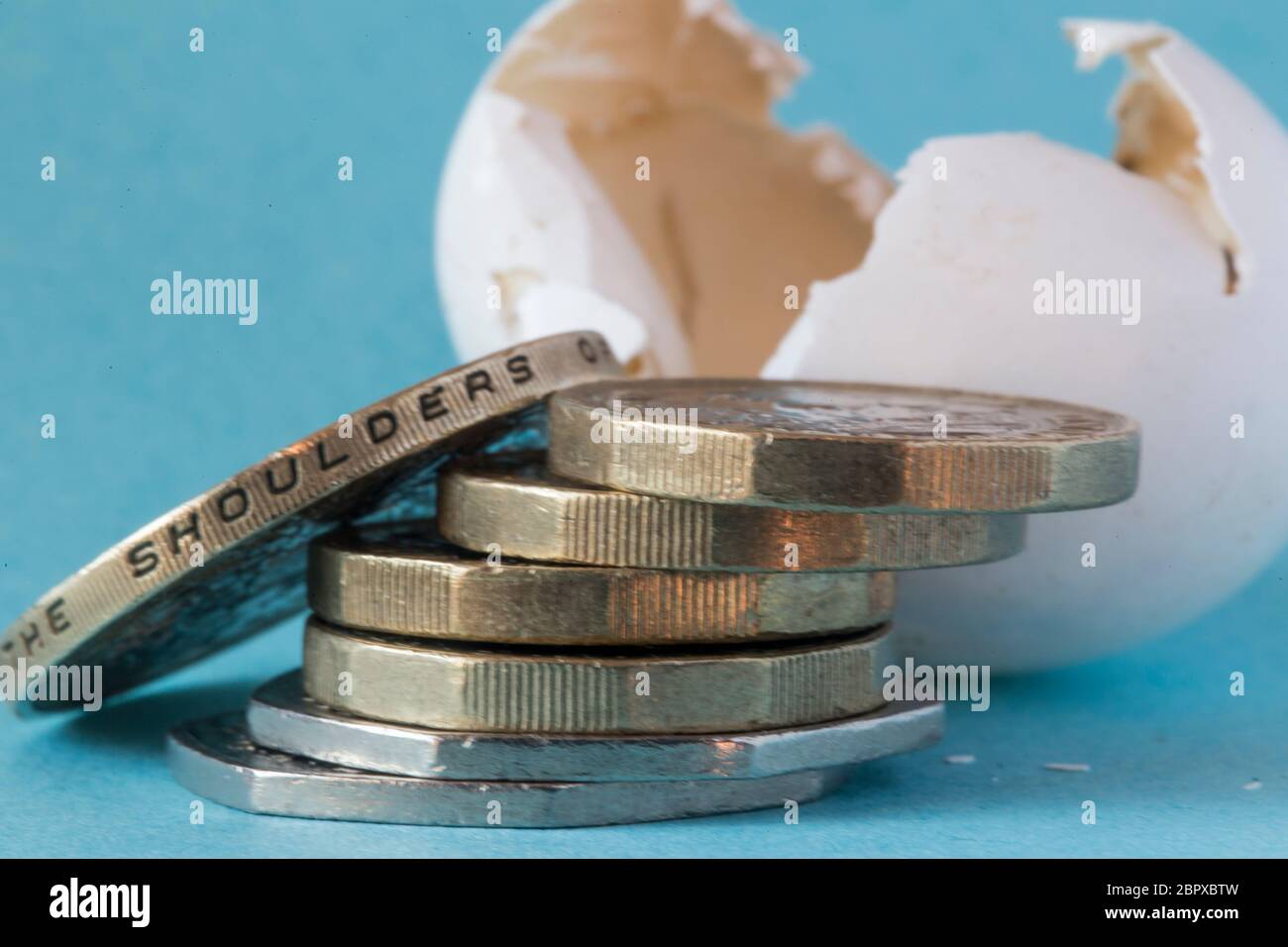 Ethically sourced wild bird's egg shell shot close up with British Pound Coins, a Two pound coin and some 50 pence pieces. Stock Photo