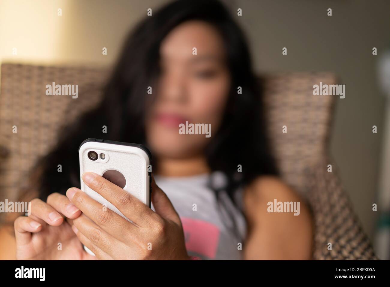 Concept image of boredom or isolation as woman  uses a mobile phone during a quarantine period in the COVID-19 Pandemic 2020 Stock Photo