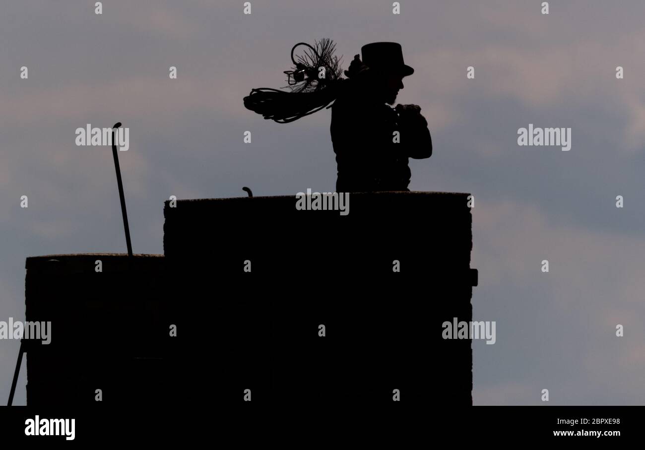 15 May 2020, Saxony, Dresden: A chimney sweep walks along a roof with his chimney sweeping tool. Photo: Robert Michael/dpa-Zentralbild/ZB Stock Photo