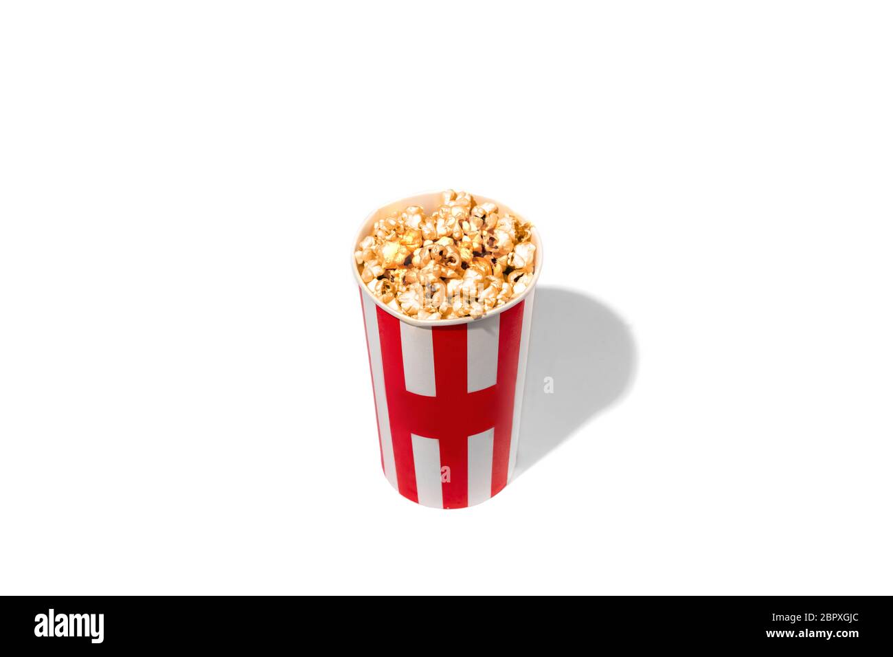 Striped white red bucket full of popcorn isolated on white studio background with copyspace for advertising. Entertainment, food, traditional snacks, time for cinema and having fun, tasty. Stock Photo