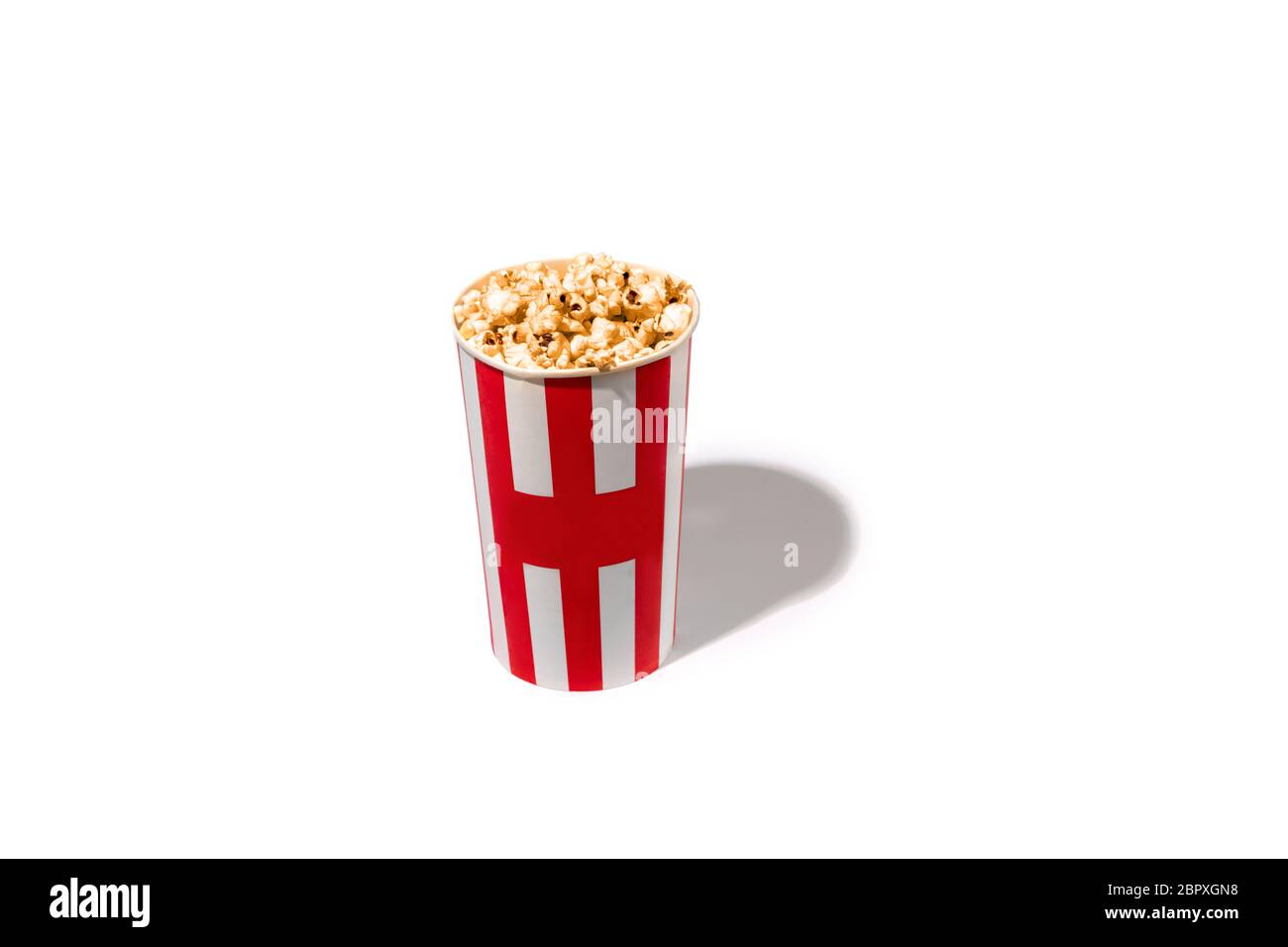 Striped white red bucket full of popcorn isolated on white studio background with copyspace for advertising. Entertainment, food, traditional snacks, time for cinema and having fun, tasty. Stock Photo