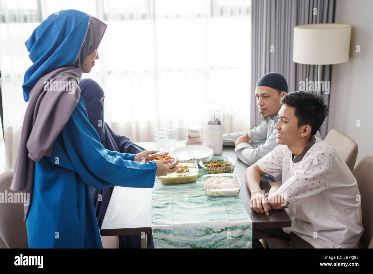mother muslim serving food for family in the dining room Stock Photo