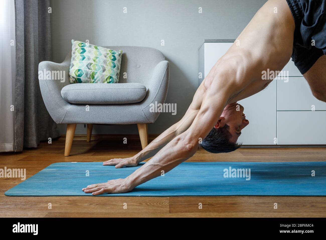 Man in upward dog pose doing vinyasa flow at home. Practising pilates and yoga at home Stock Photo