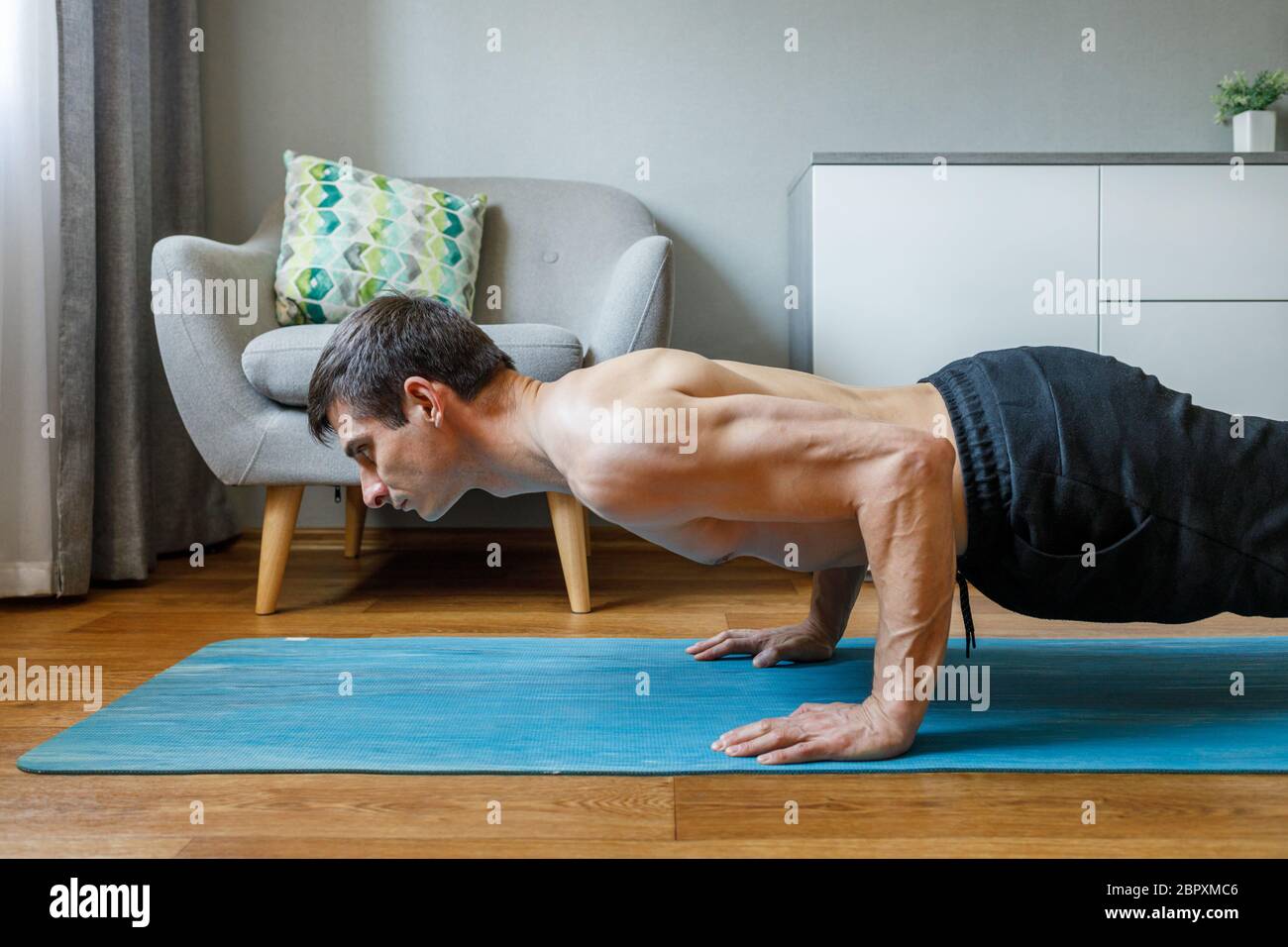 Man in chaturanga pose doing vinyasa flow at home. Practising pilates and yoga at home Stock Photo