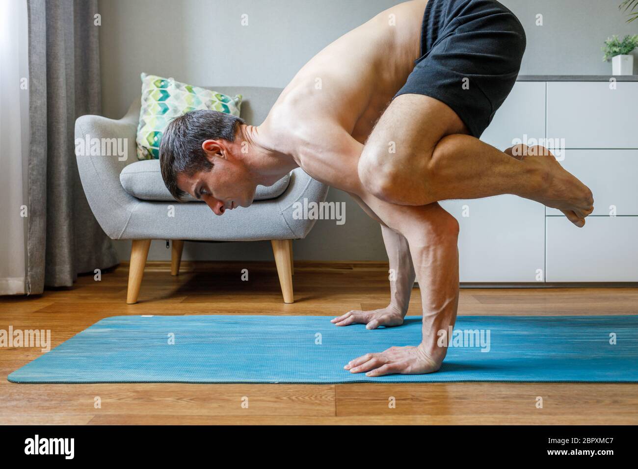 Man In Bakasana Pose Doing Vinyasa Yoga Flow At Home Practising Pilates And Yoga At Home Stock Photo Alamy