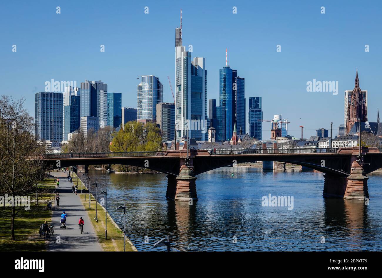 Frankfurt am Main, Hesse, Germany - Walkers on the banks of the Main during the Corona crisis with a ban on contact, in the back skyline of Frankfurt Stock Photo