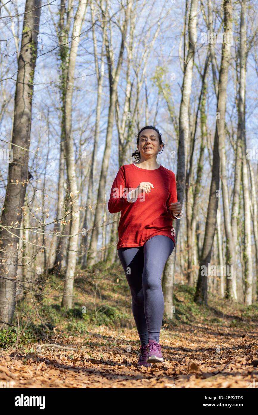 Pretty Spanish woman jogging in the forest in autumn time Stock Photo