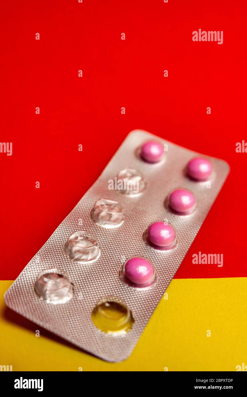 Closeup of a pack of tablets under the lights against a red and yellow background medical