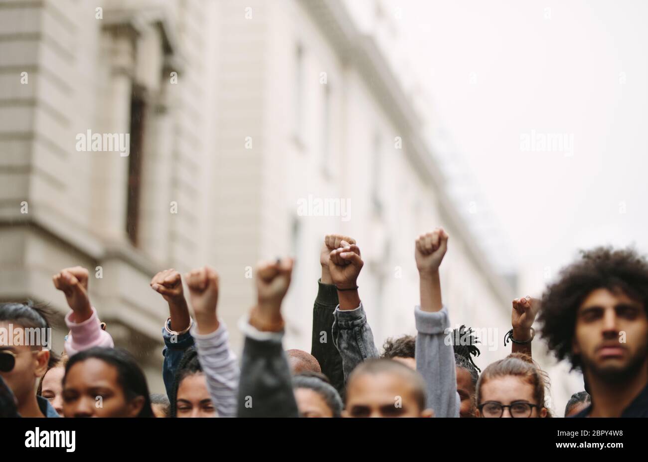 Arms raised in protest. Group of protestors fists raised up in the air. Stock Photo