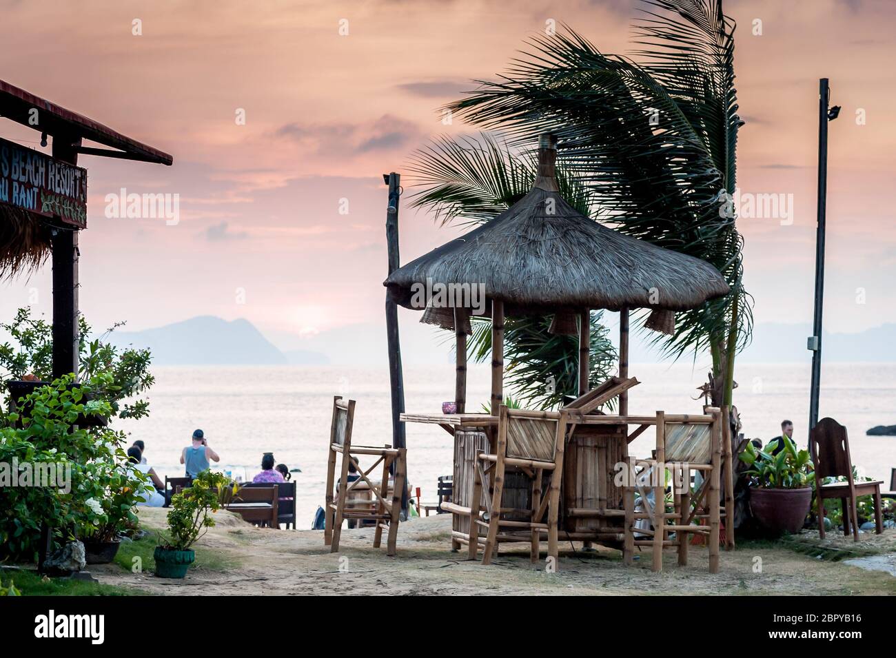 A beach hut cafe with the setting sun behind at Las Cabanas Beach Resort, El Nido, Palawan, The Philippines. Stock Photo