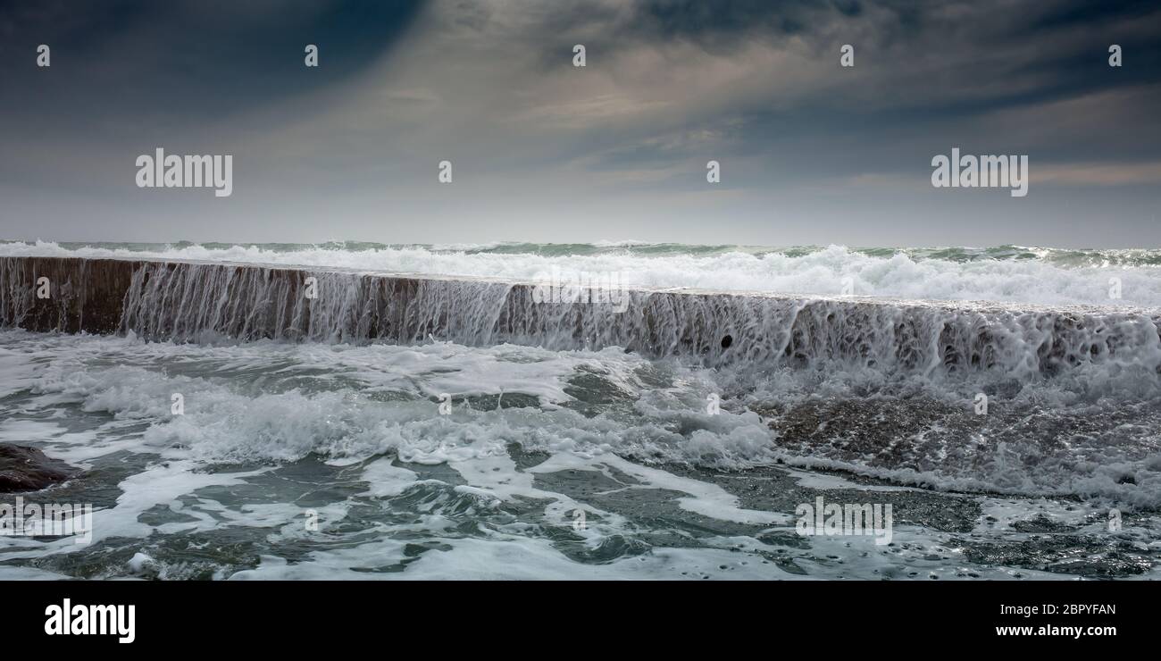 White foam waves roll through breakwater Stock Photo