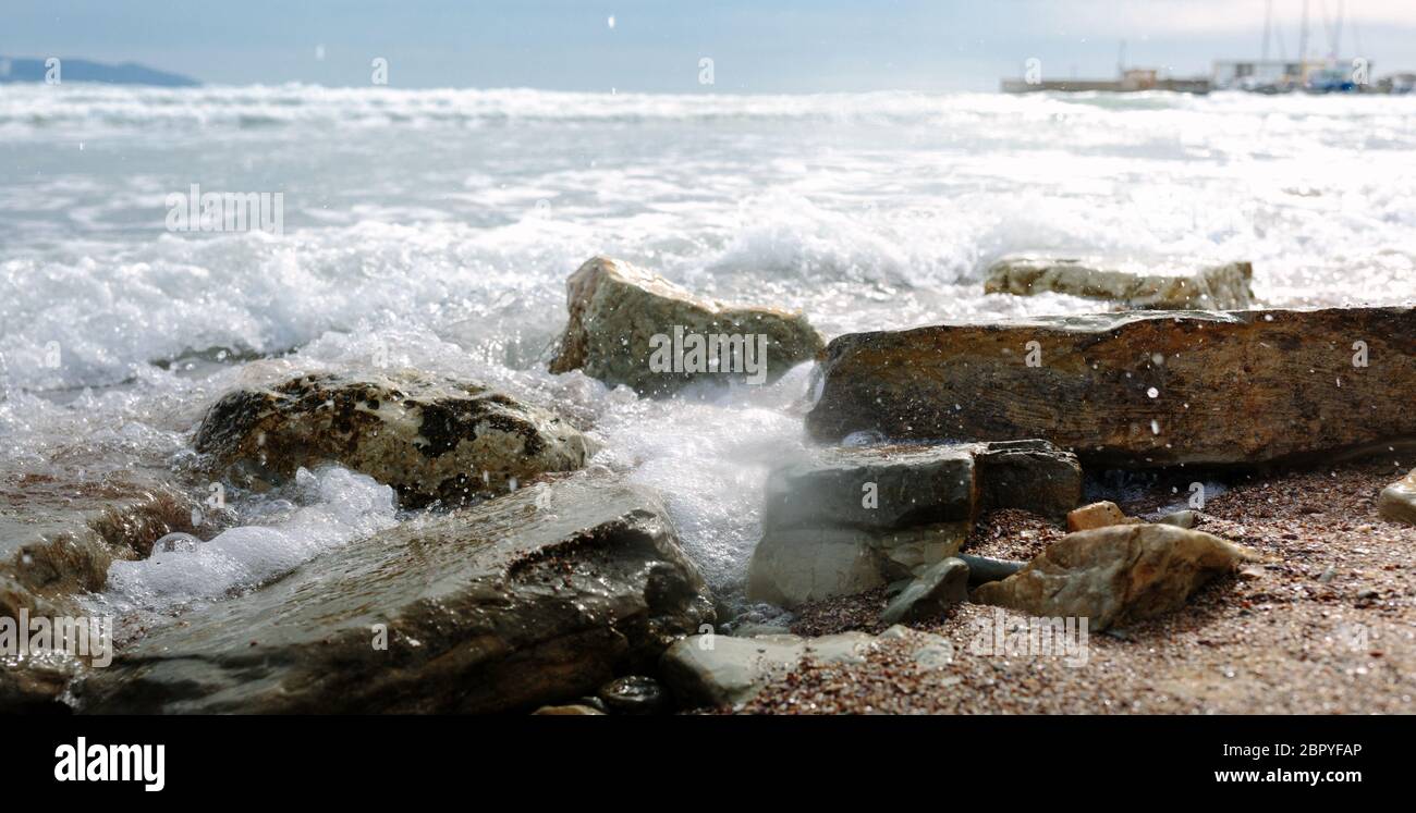 Foamy waves roll on rocky beach Stock Photo - Alamy
