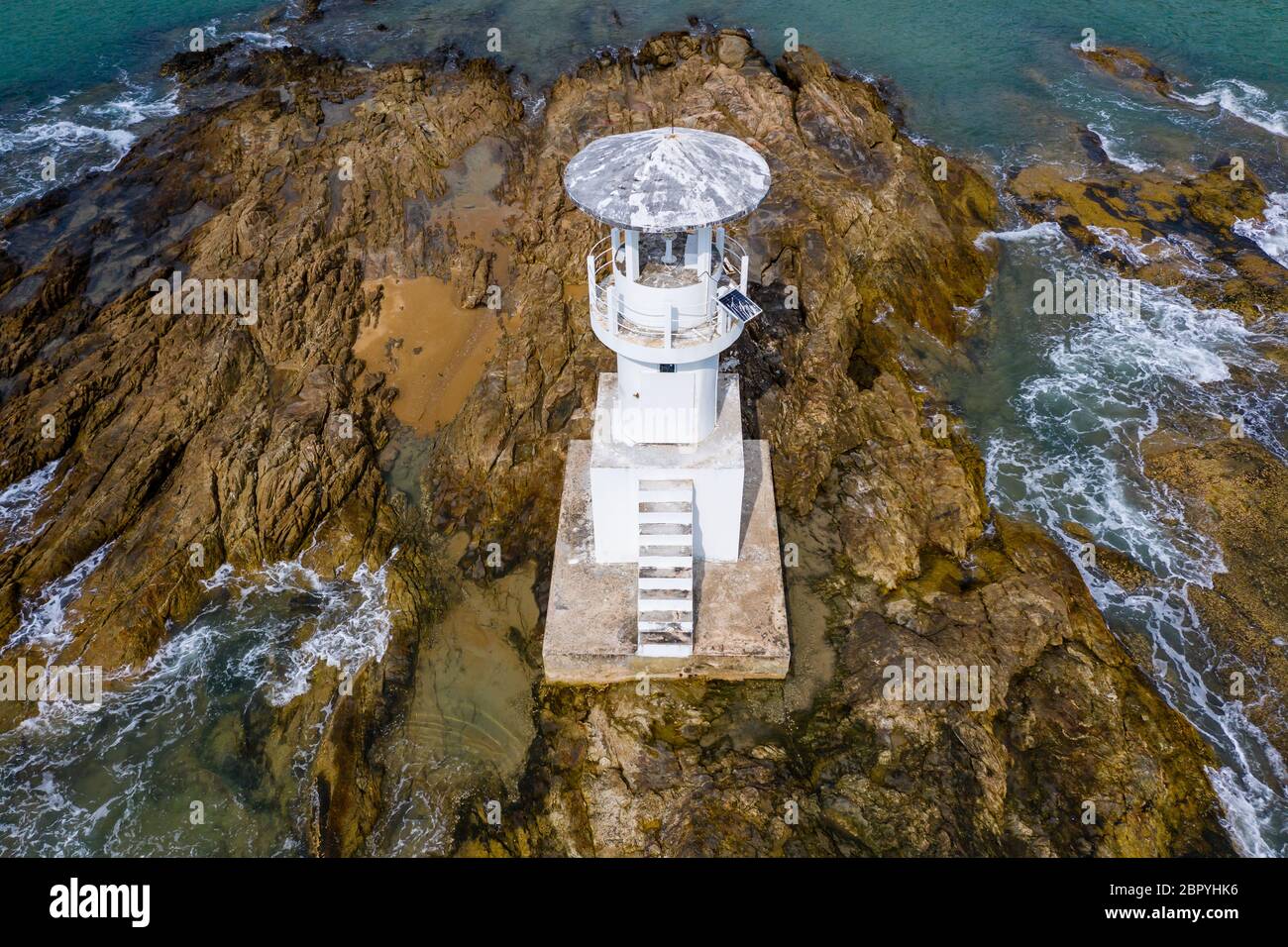 Drone view of a small offshore lighthouse located on a small, rocky island Stock Photo