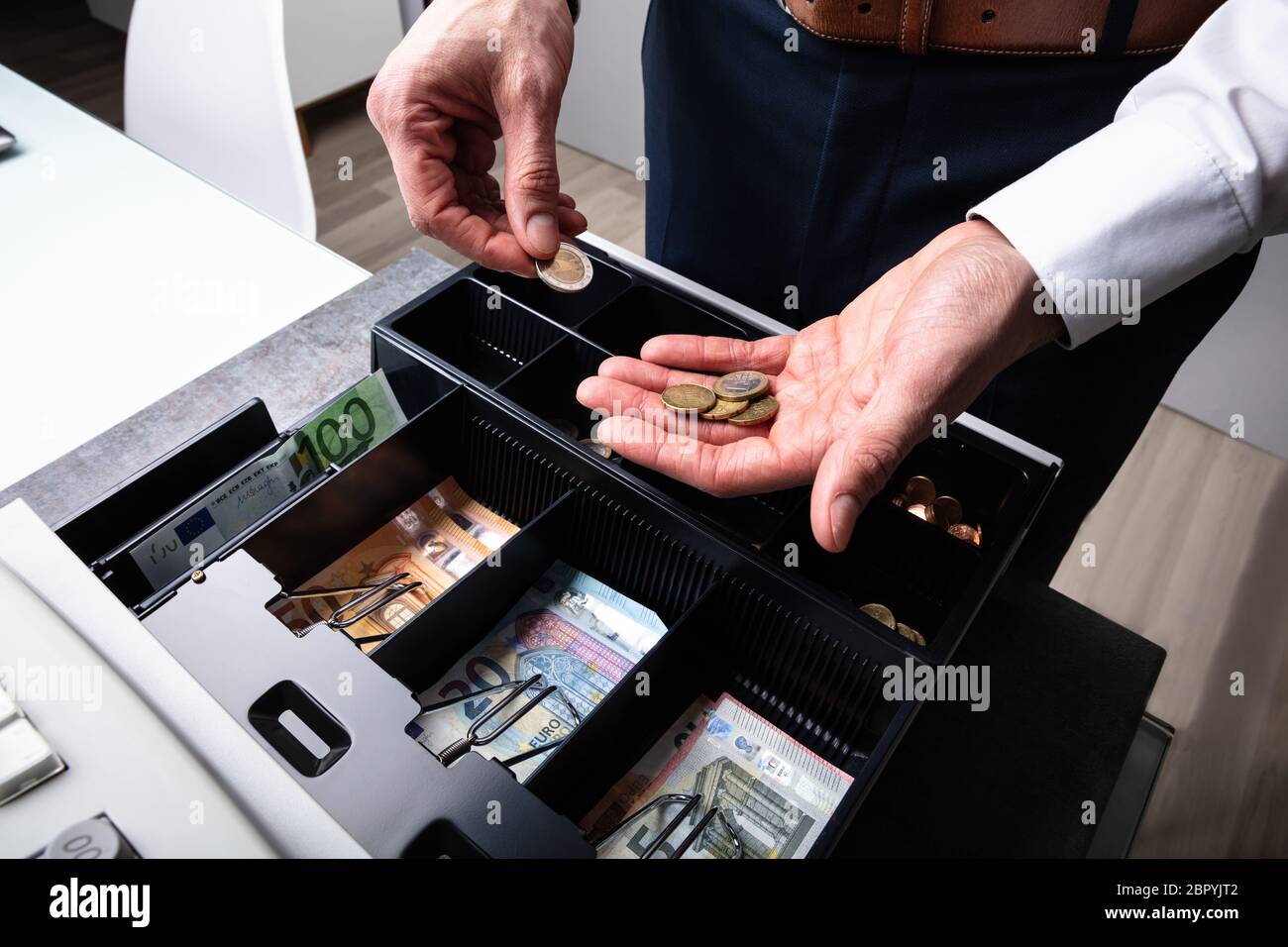 An Overhead View Of Cashier's Hand Taking Banknote From Opened Till Stock Photo