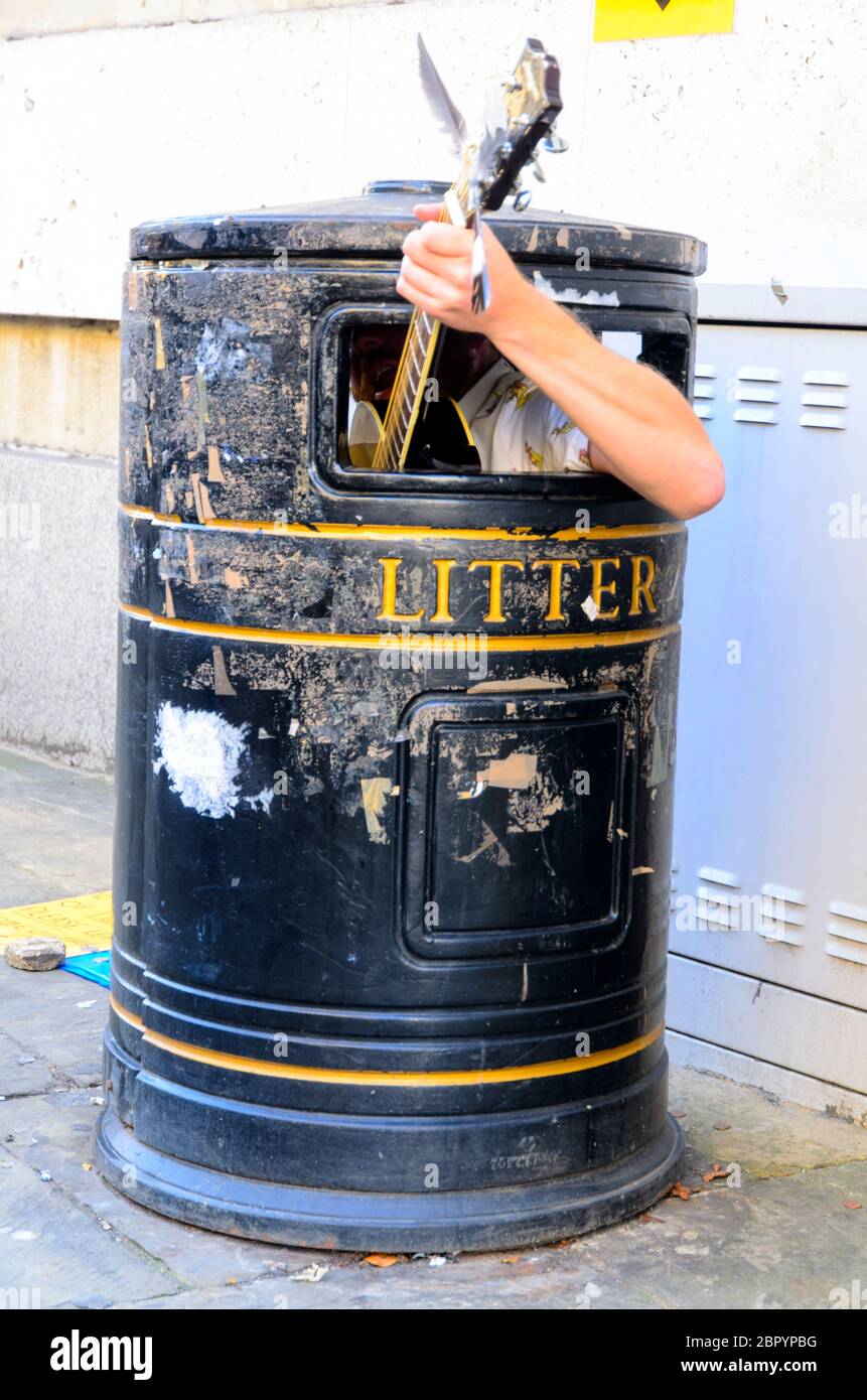 A busker playing guitar in a litter bin - Cambridge, England Stock Photo