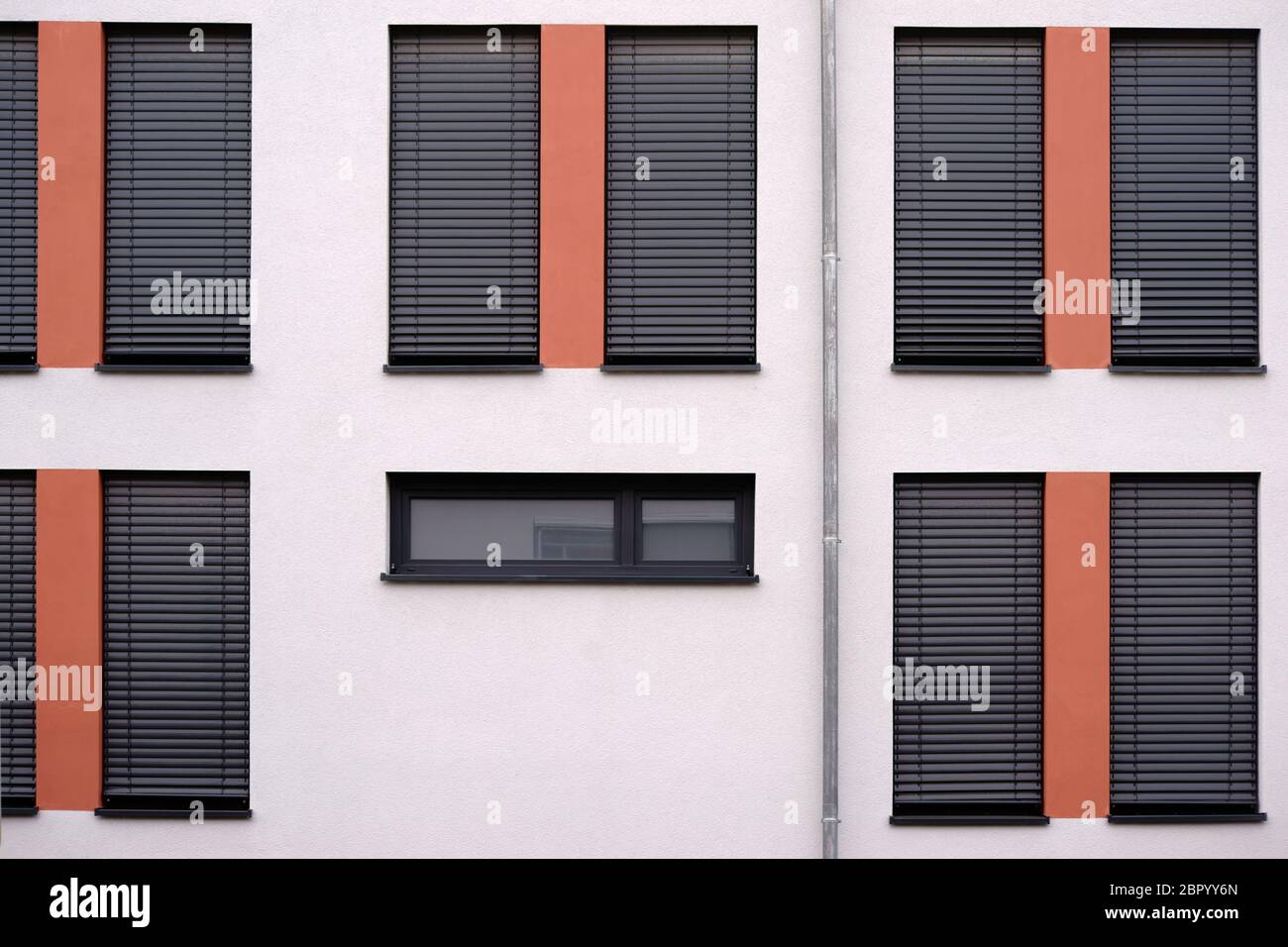 The modern facade of a modern residential building with lowered metal blinds and a gutter. Stock Photo