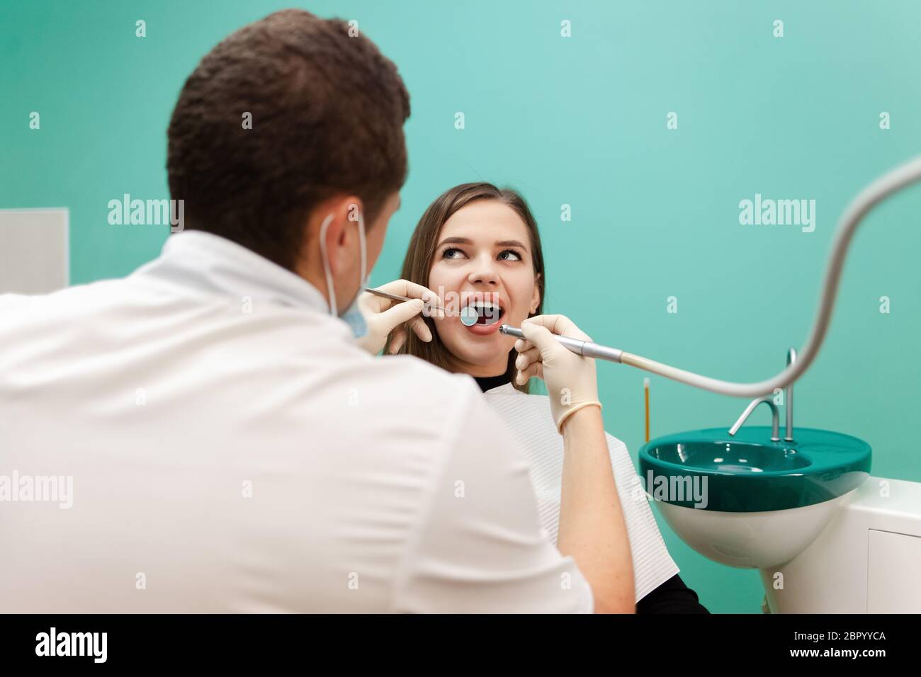 Dentist with a drill and a mirror is treating a patient teeth Stock ...
