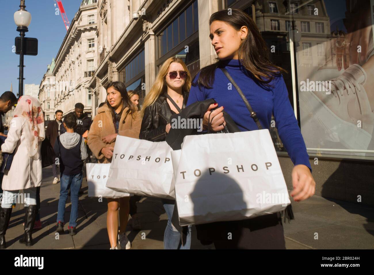 Three women with identical Top Shop bags walking in Oxford Street. Stock Photo