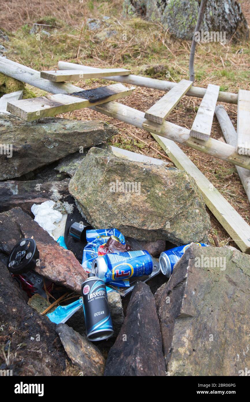 Litter left by youths camped overnight on Todd Crag, Ambleside, Lake District, UK, who also pulled down a tree protecting fence to light a fire with. Stock Photo