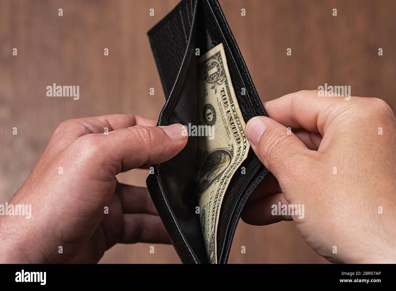 Black leather wallet with one dollar in the hands of a man. Bankruptcy ...