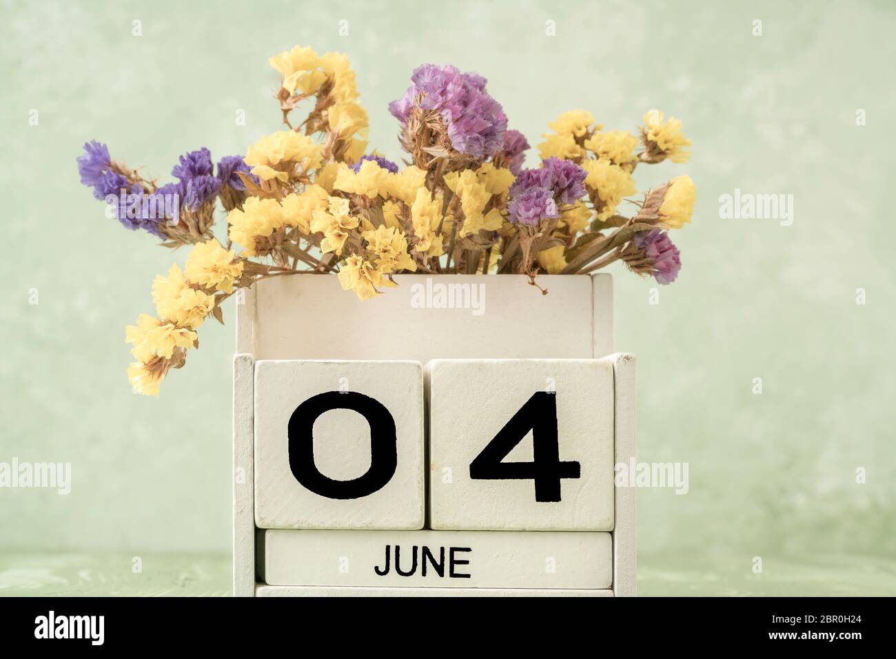 White cube calendar for june decorated with flowers over green ...