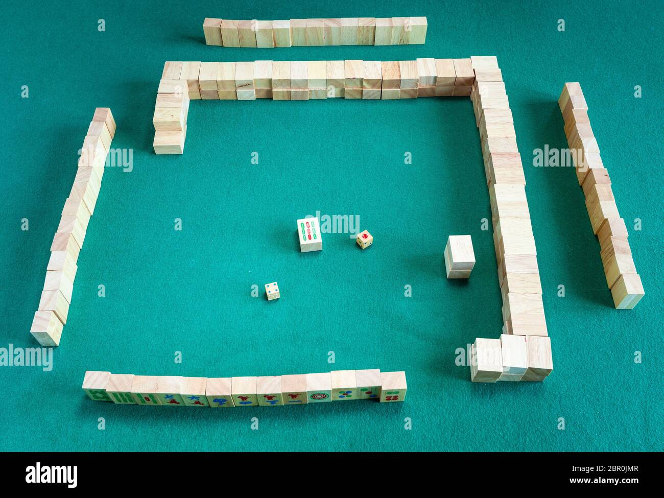 beginning of play of mahjong (disassembling the wall), tile-based chinese strategy board game on green baize table Stock Photo