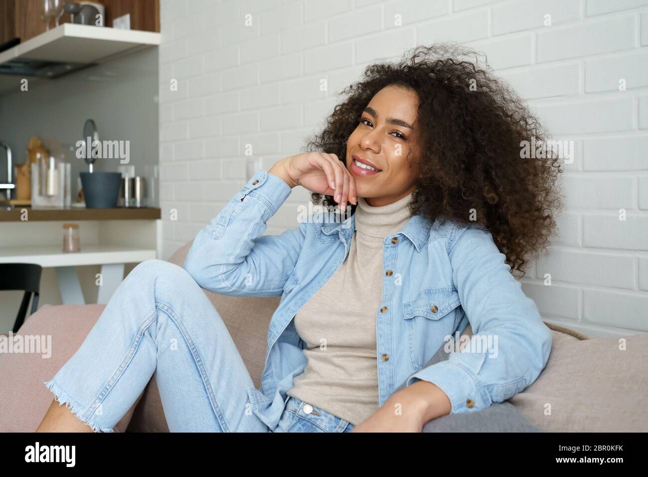 Happy relaxed african woman lounge on comfortable sofa, portrait. Stock Photo
