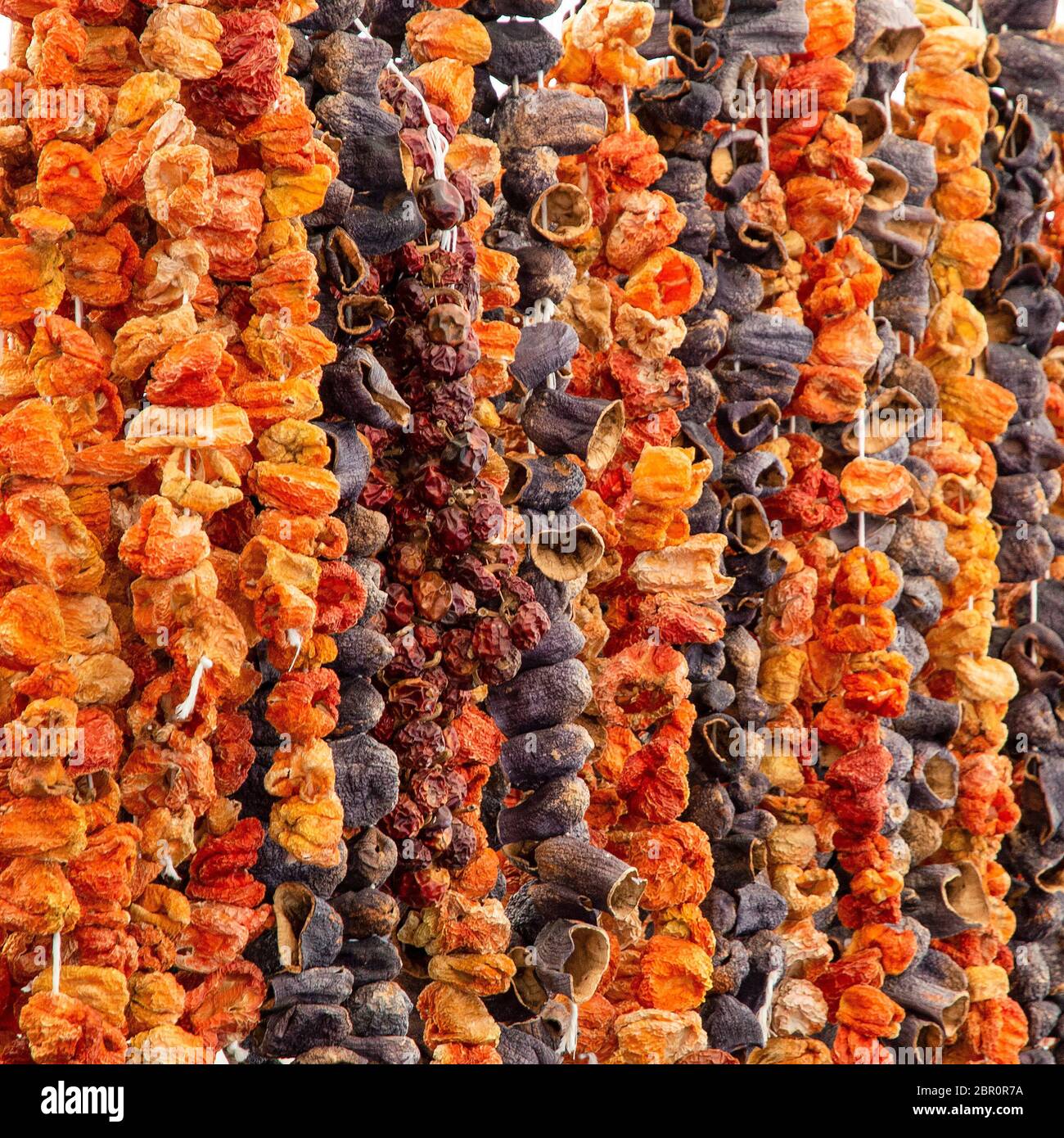 Eastern spices sun dried paprika peppers pods and eggplants fruits hanging at Turkish grocery market Stock Photo