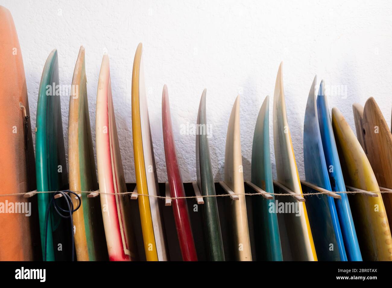 View of a set of colorful surfboards put in a rack by the wall in a