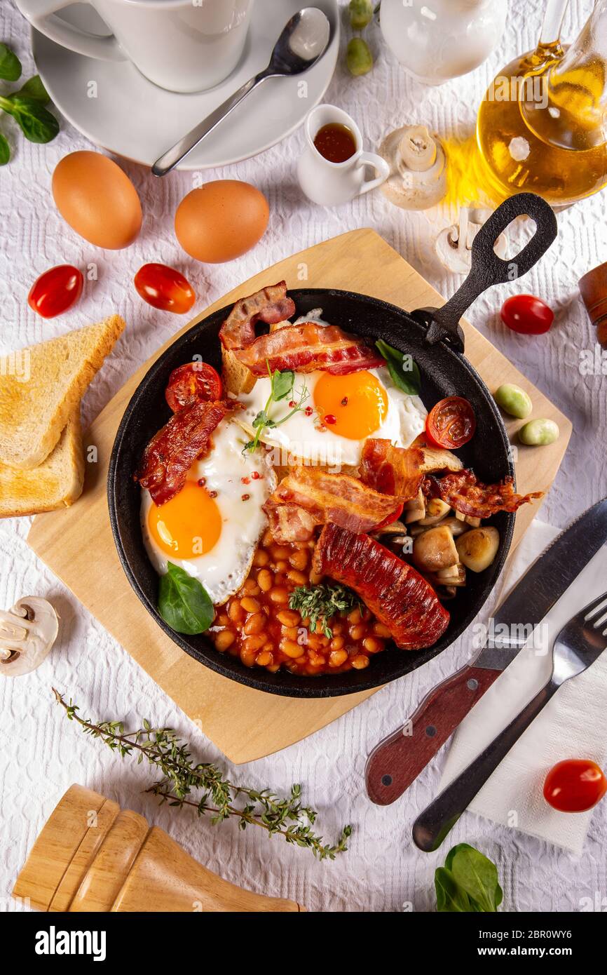 Cook Breakfeast English Breakfast served in cooking pan with fried eggs, sausages ...