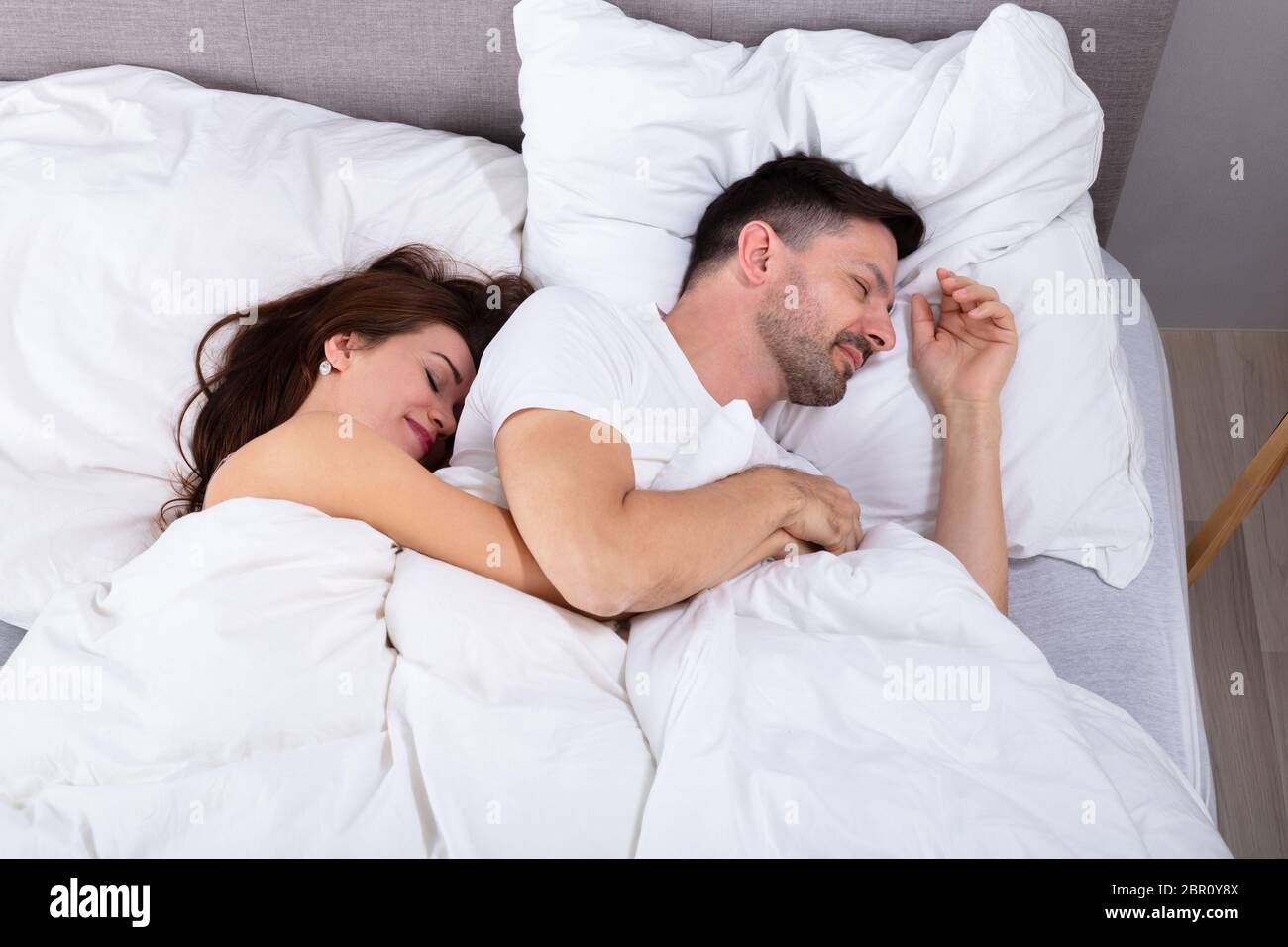Young Loving Couple Sleeping On Bed With White Blanket Stock Photo
