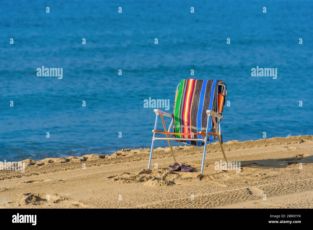 Empty chair on sandy beach, blue sea background, Costa Dorada, Spain. copy space Stock Photo