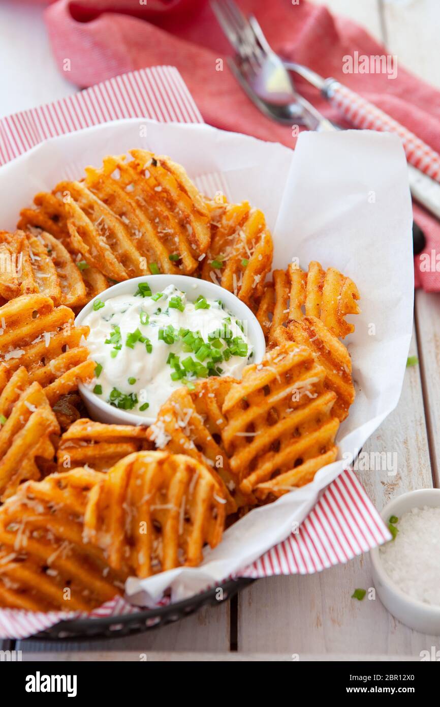 Crunchy waffle fries with sour cream dip served in a basket Stock Photo Alamy