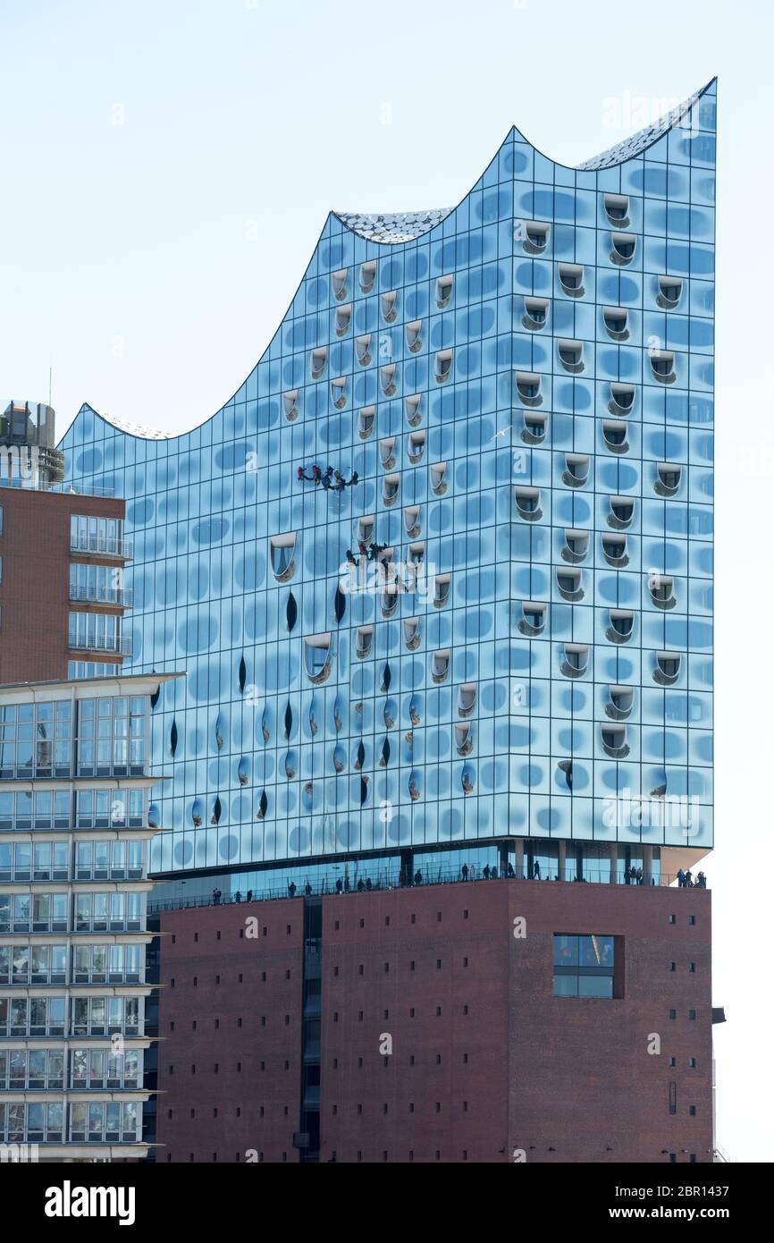 window cleaner at the high facade outside the concert hall elbphilharmonie in hamburg Stock Photo