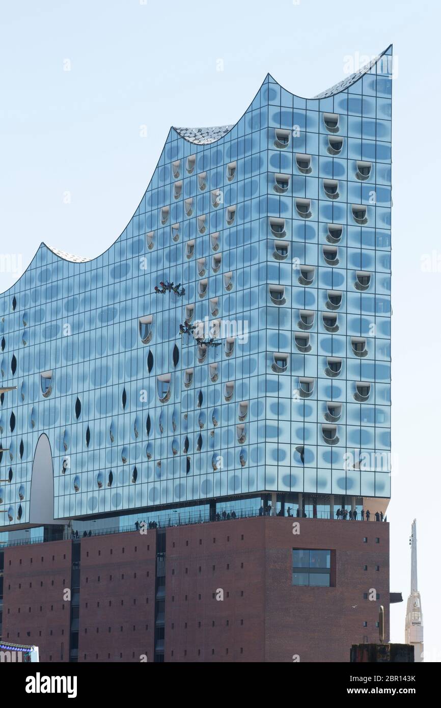 window cleaner at the high facade outside the concert hall elbphilharmonie in hamburg Stock Photo