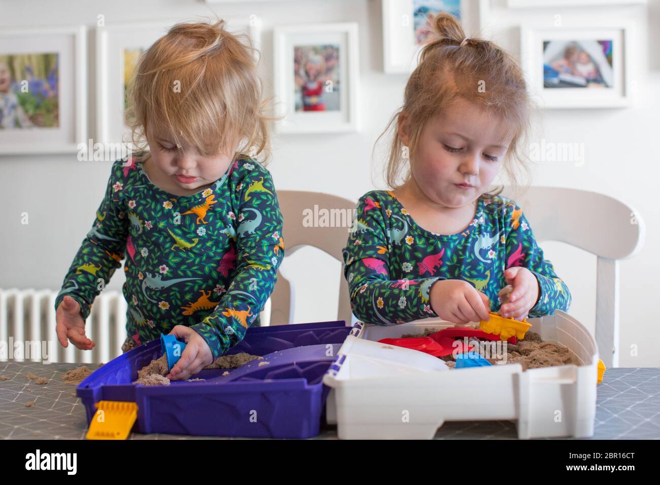 Two young children playing indoors at the table with a sand box, UK Stock Photo
