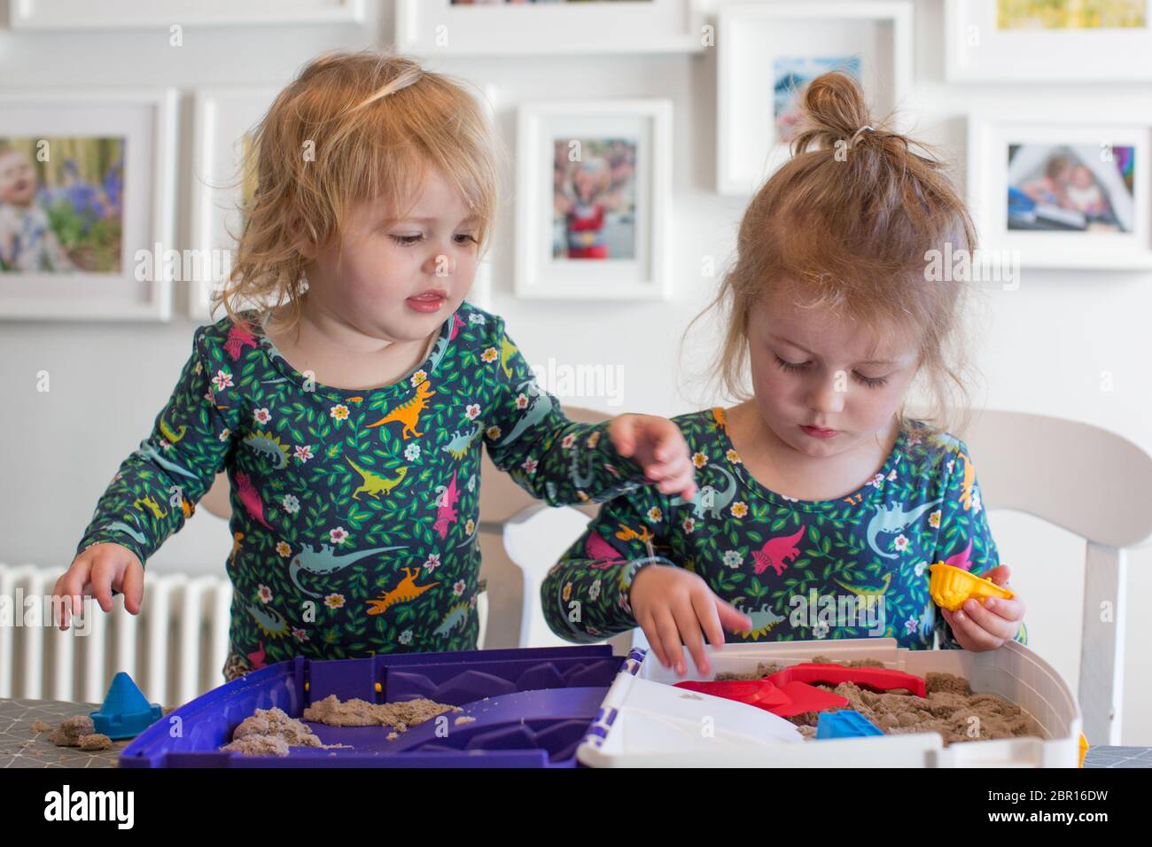 Two young children playing indoors at the table with a sand box, UK Stock Photo
