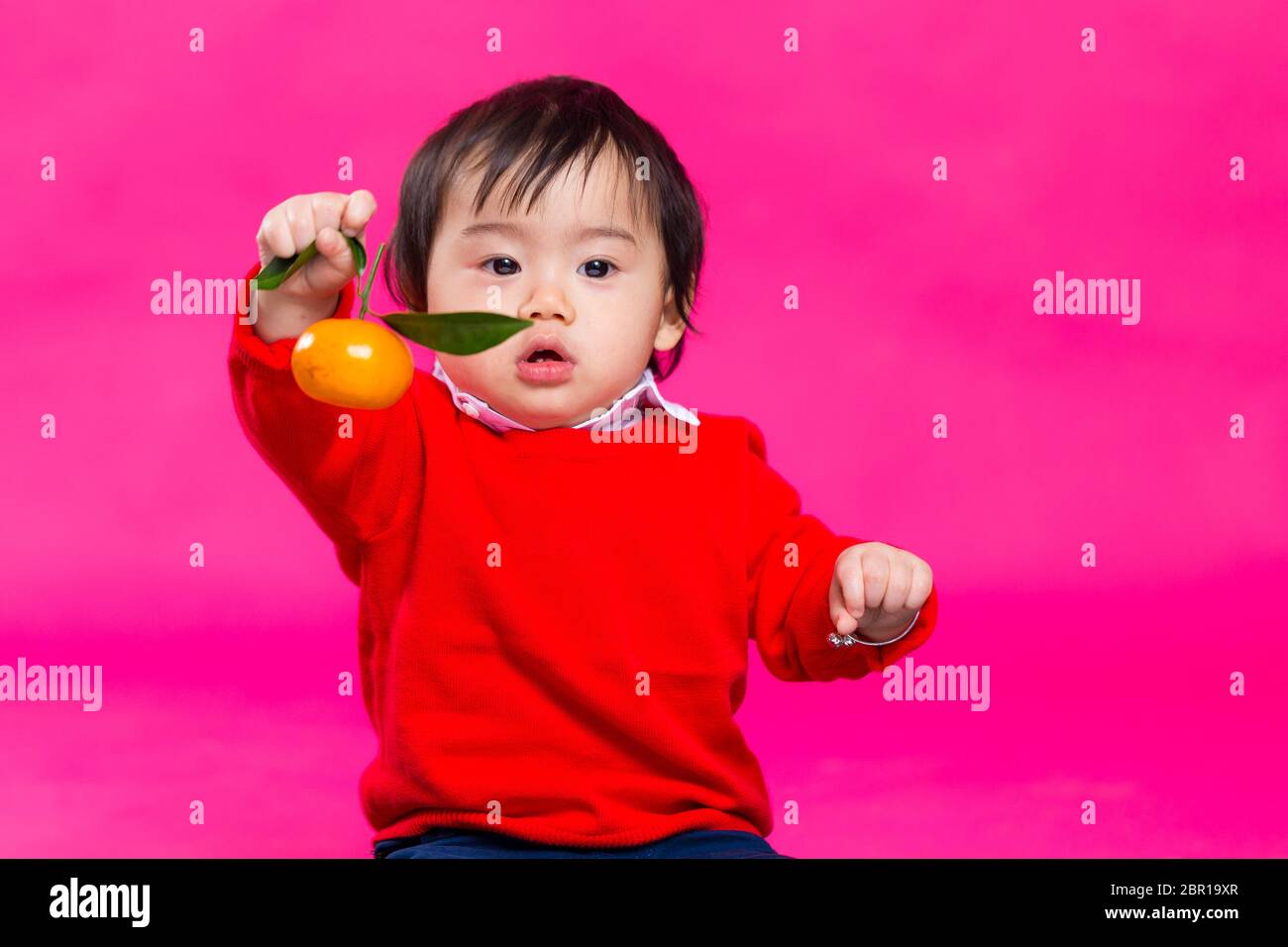 Asian baby boy holding a tangerine for lunar new year Stock Photo