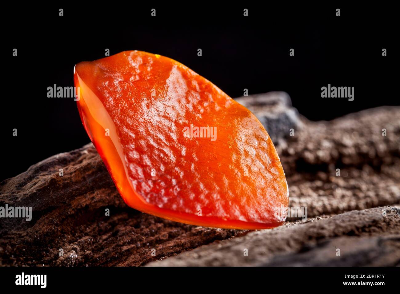 A piece of yellow semi transparent natural amber, classification color honey or cognac, has cracks on its surface. Polished, natural shape. Placed on Stock Photo