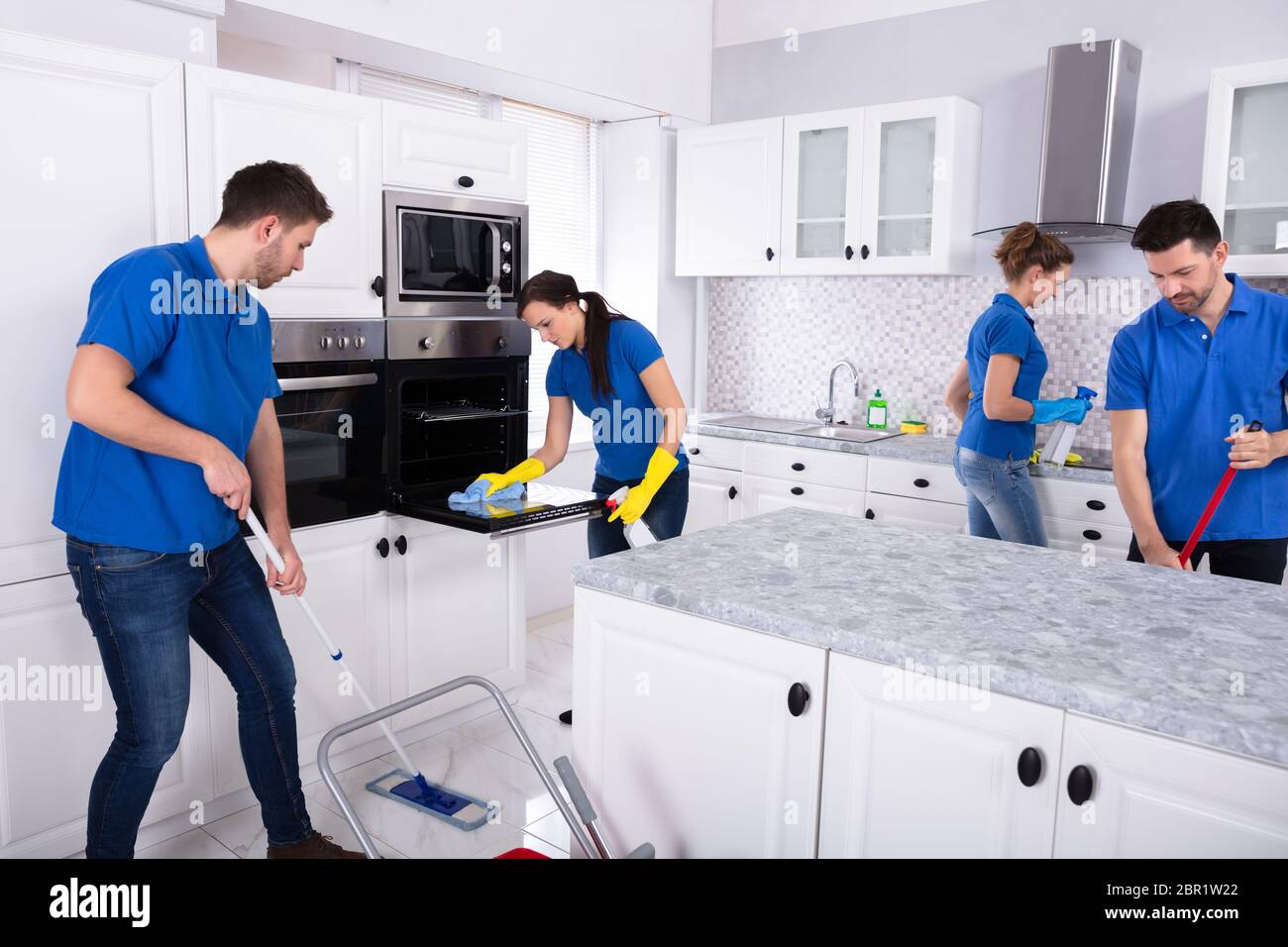 Group Of Young Janitors In Uniform Cleaning Kitchen At Home Stock Photo ...