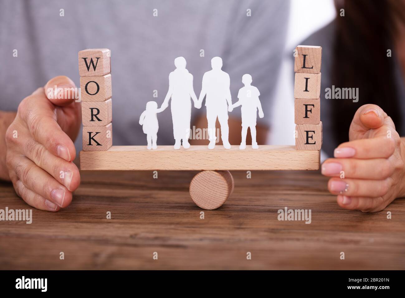 Couple Protecting Work And Life Balance With Family Figures Standing ...