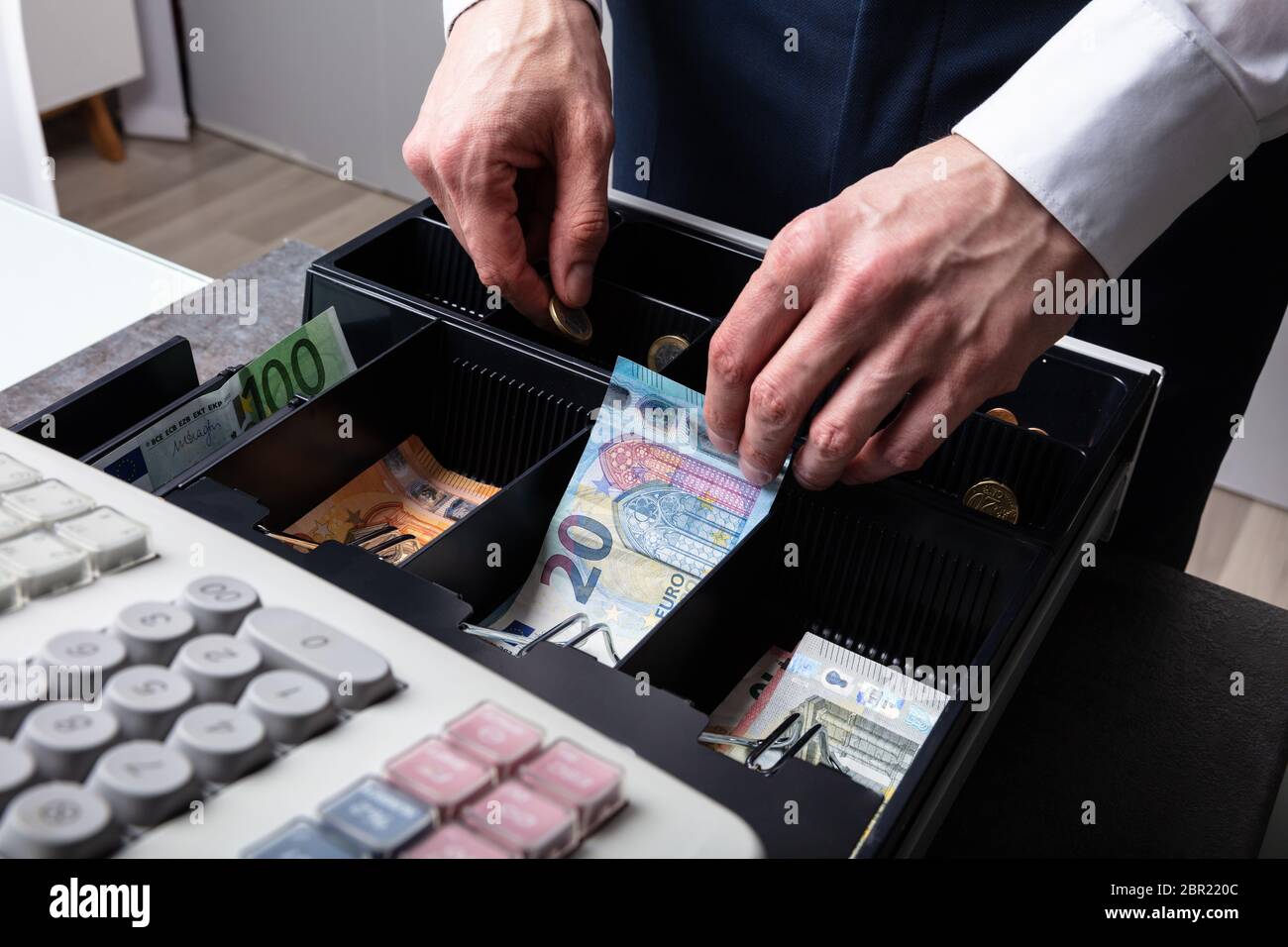 An Overhead View Of Cashier's Hand Taking Banknote From Opened Till Stock Photo